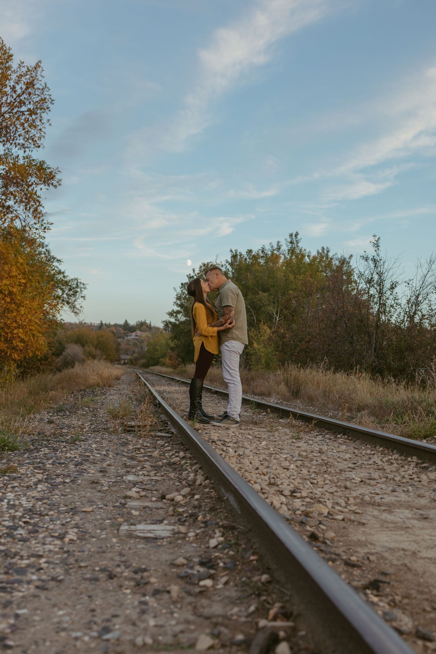 Couple walking along rustic train tracks during autumn sunset photoshoot.