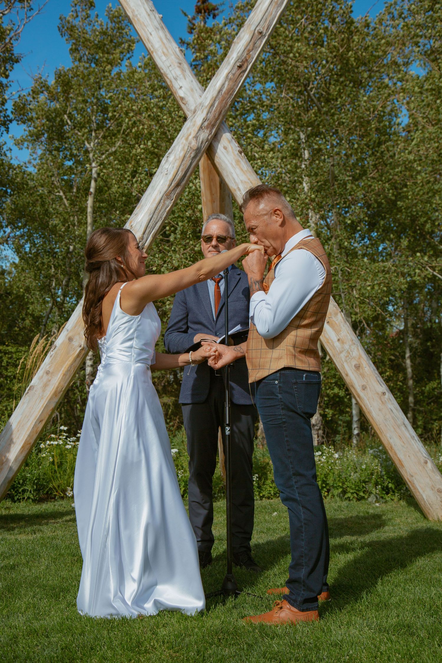 A light blue dress contrasts against wooden beams during an outdoor ceremony.