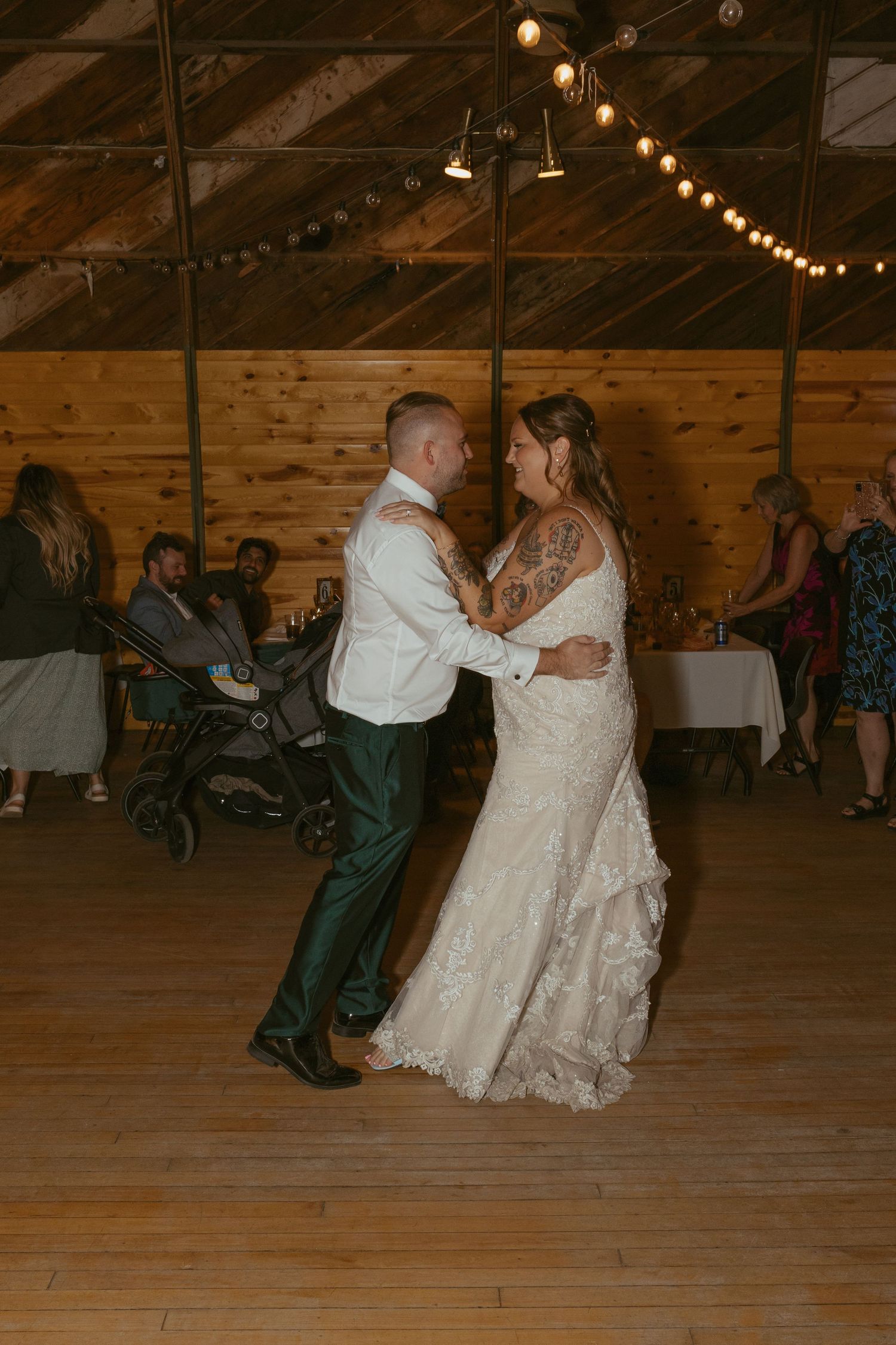 Wedding dance in a rustic barn venue with string lights and wooden interior.