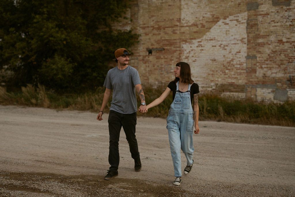 A couple walks together on a dirt path in a romantic outdoor setting at sunset.