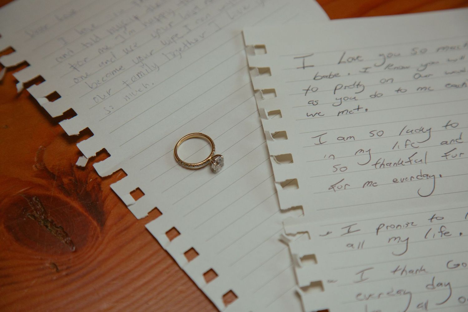 Gold engagement ring on spiral notebook with handwritten love notes.