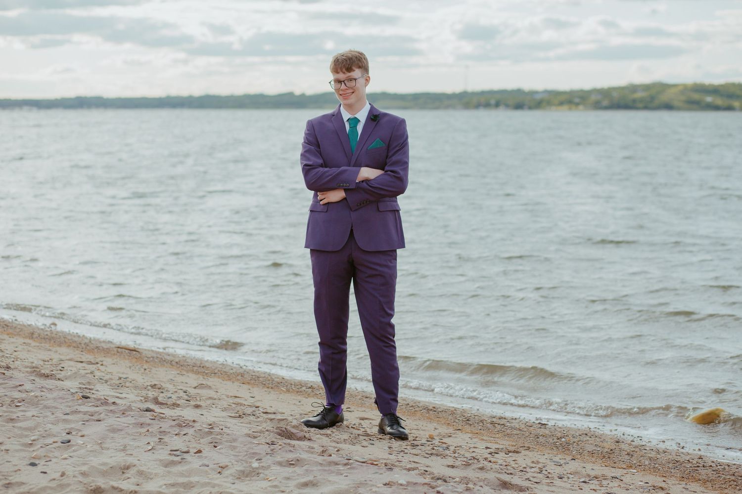A formal photo session taking place on a beach with water in the background.