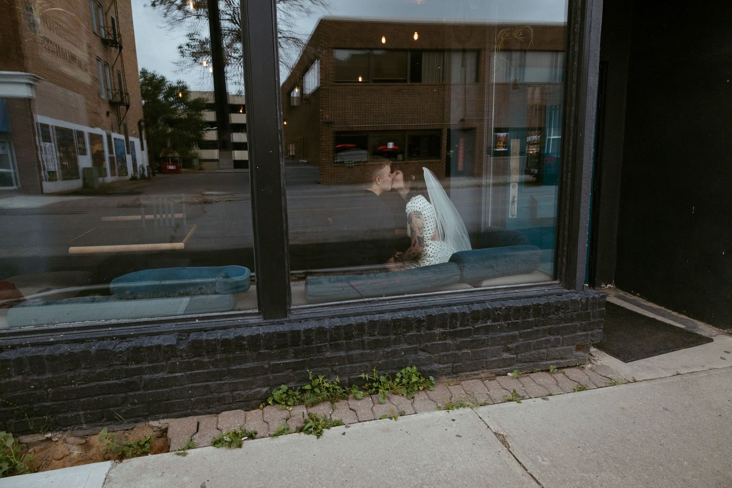Empty sidewalk outside a brick storefront on an overcast day.