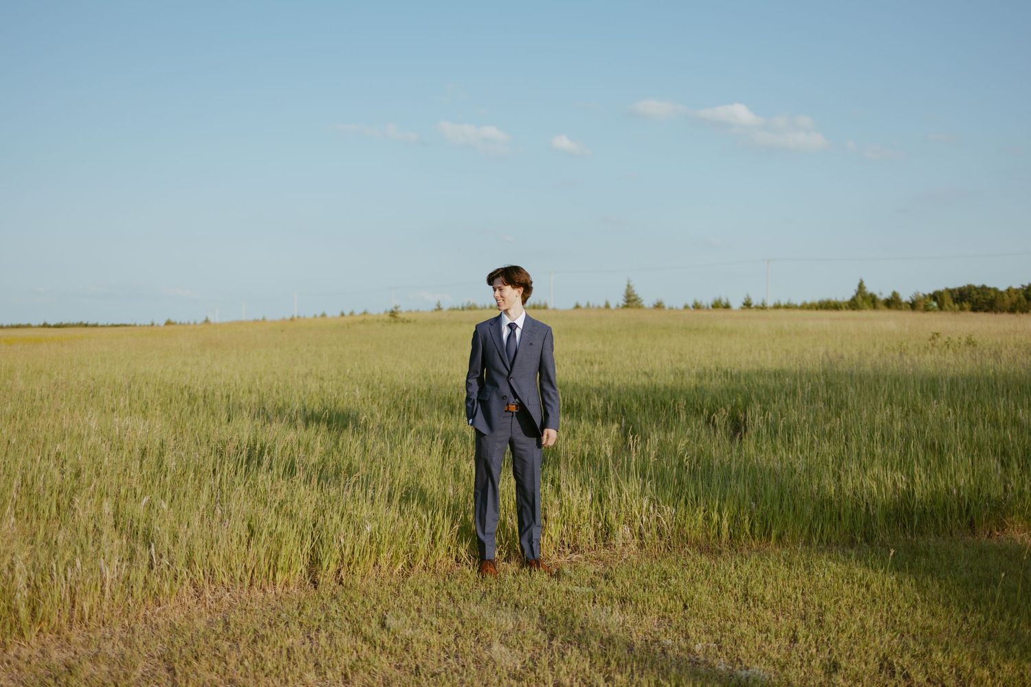 Golden wheat field stretches to horizon under blue sky during summer photo session.