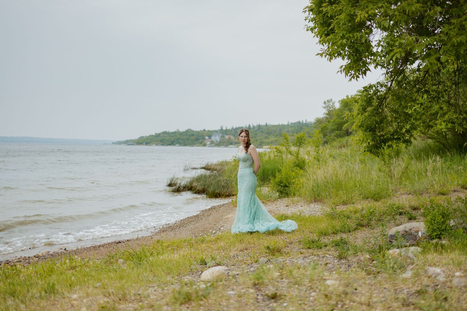 Serene lakeside scene with trees and rocky shoreline during summer.