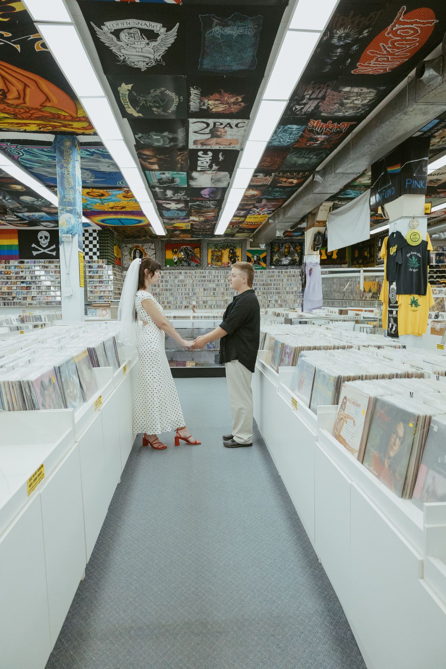 Record store interior with white display bins and music posters on ceiling.