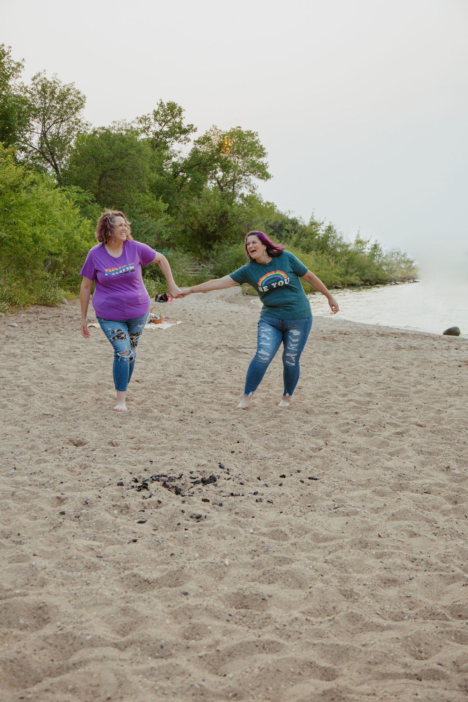 Playful couple jumping and having fun on a sandy beach.