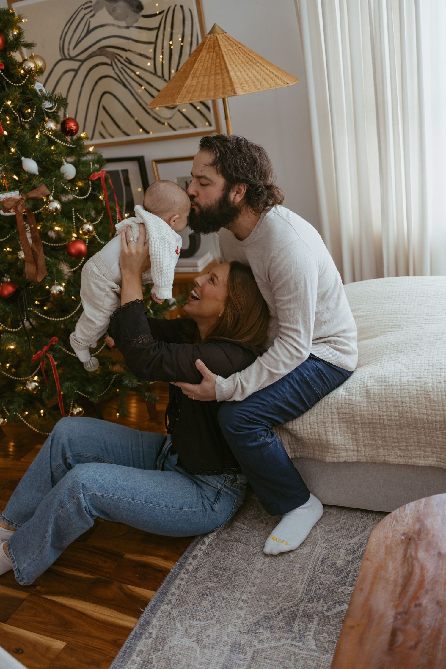 Family sharing tender holiday moment by decorated Christmas tree in cozy living room.