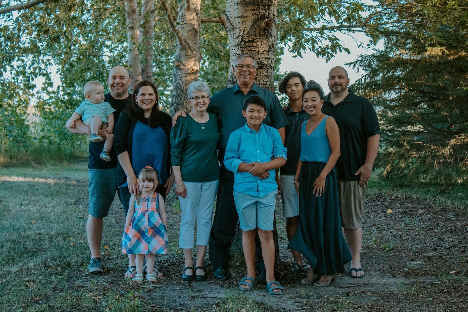 Group of people gathered outdoors among trees during golden hour.