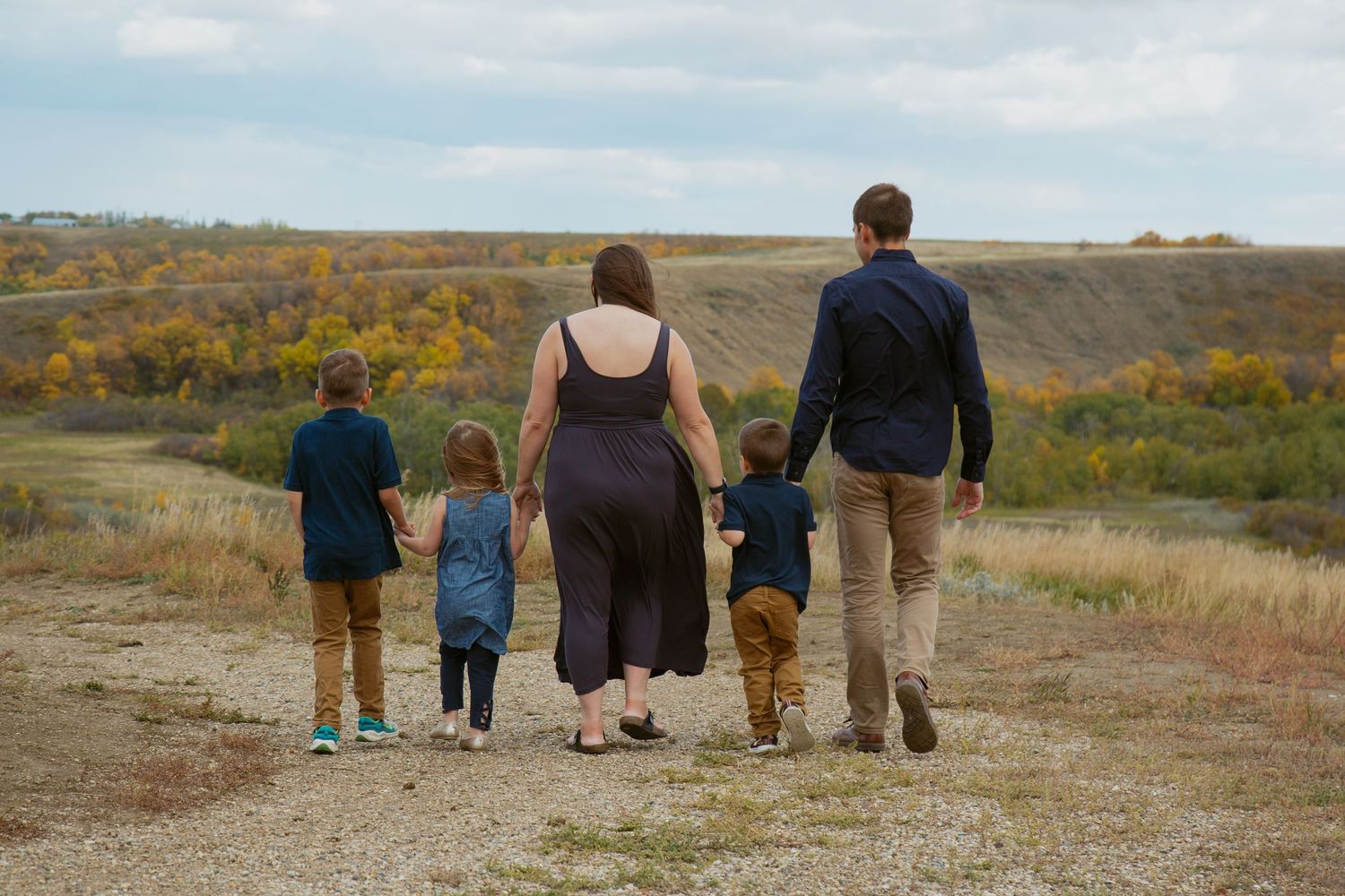 Silhouettes of people walking together against scenic fall countryside backdrop.
