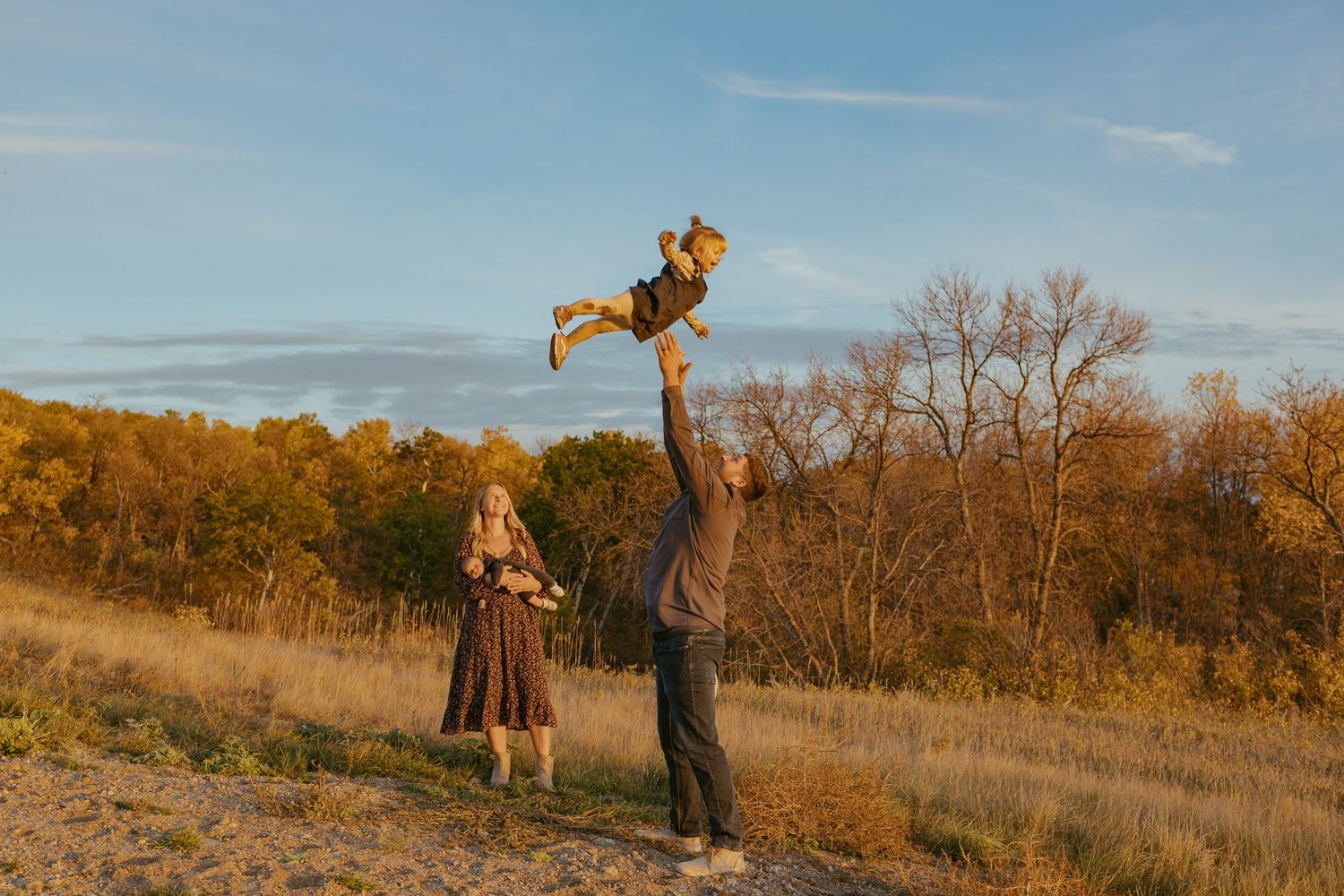 People exploring a scenic autumn prairie with golden sunlight and fall foliage.