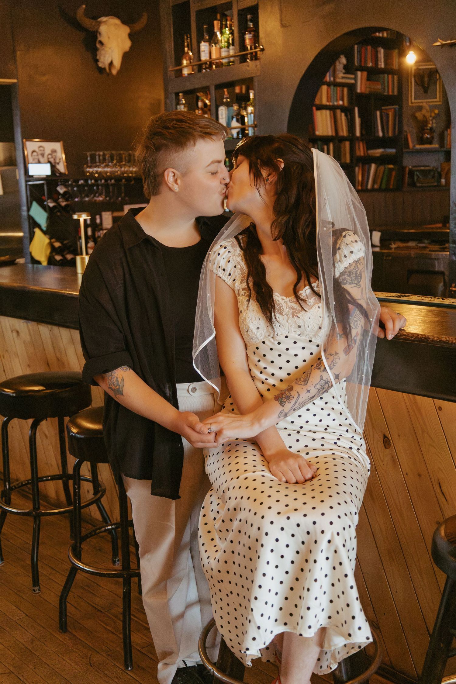 Couple sharing an intimate moment in a polka dot dress at a vintage-style bar.
