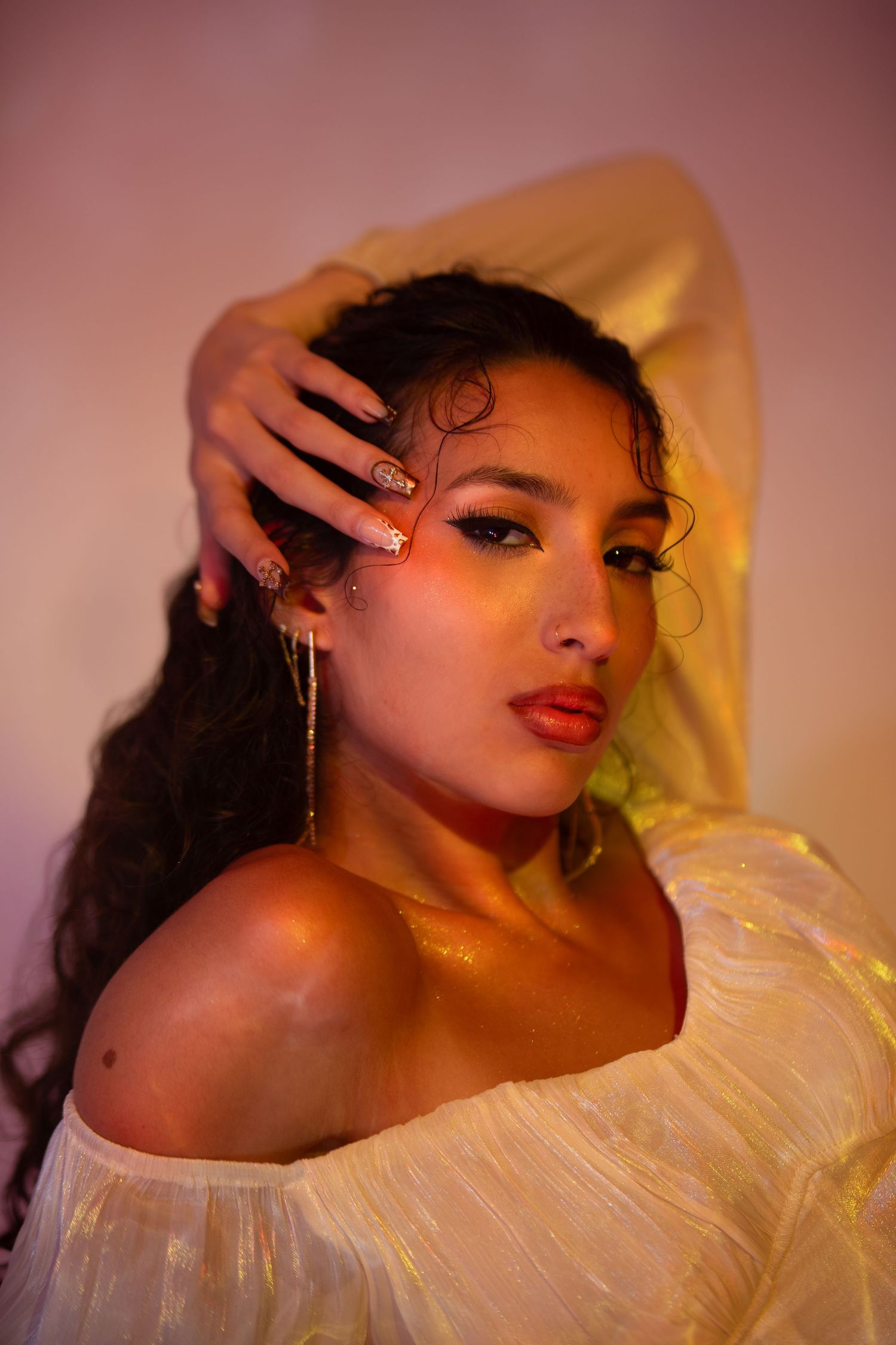 Artistic fashion portrait with dramatic lighting showing a model in a ruffled cream collar against a pink backdrop.
