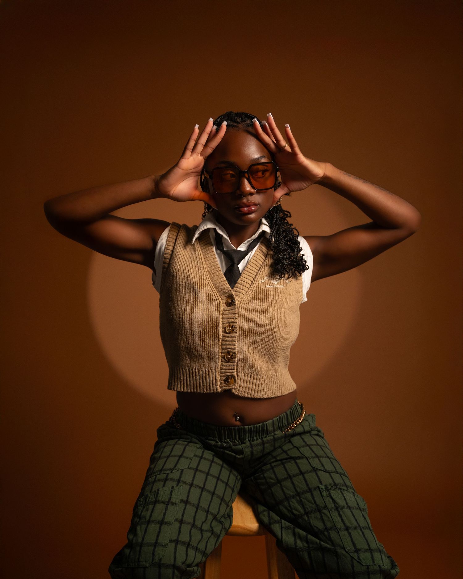 A fashion series showing a person in a beige vest and green plaid pants striking dynamic poses against a brown backdrop.