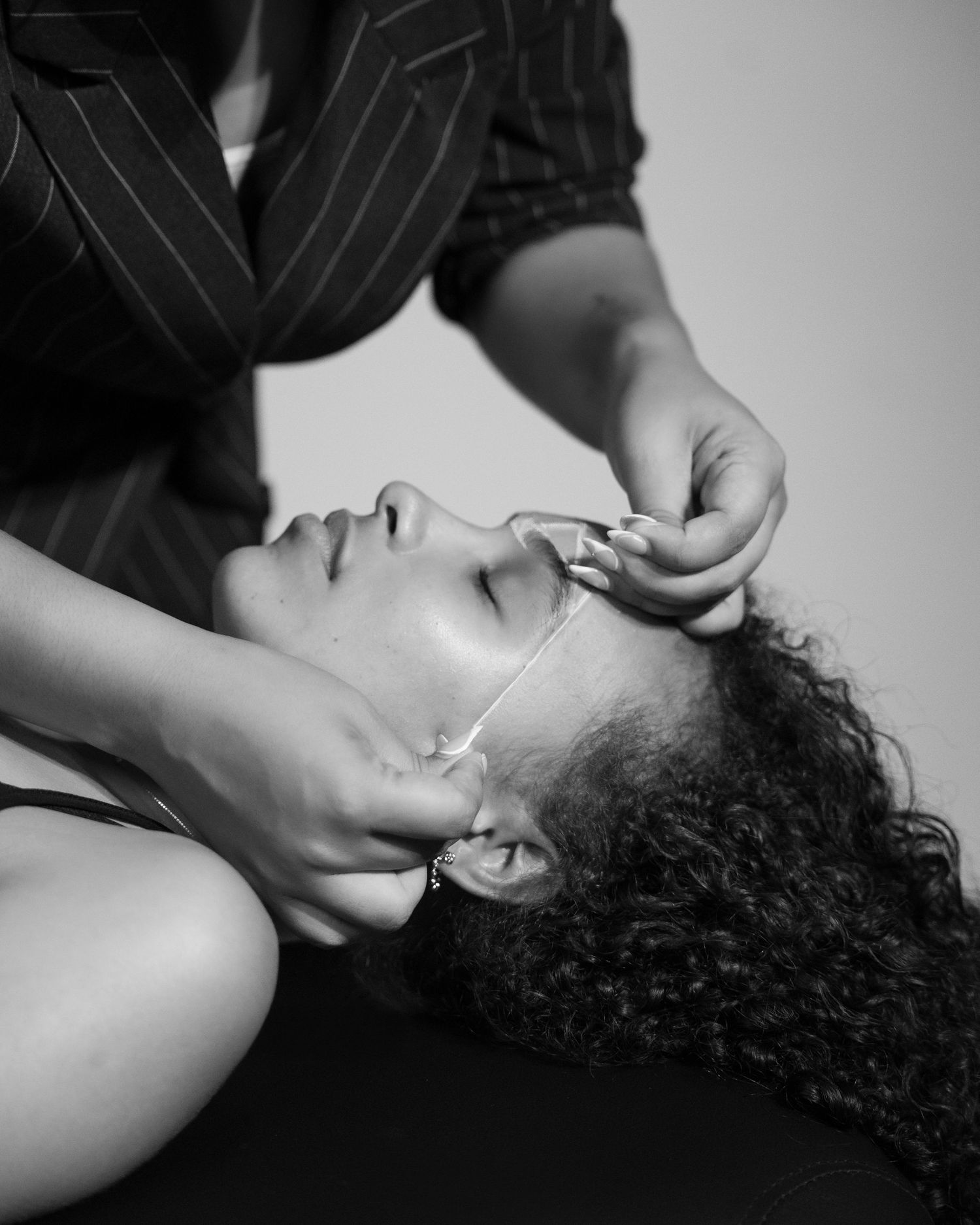 A black and white artistic portrait series showing someone reclining with curly hair in dramatic lighting.