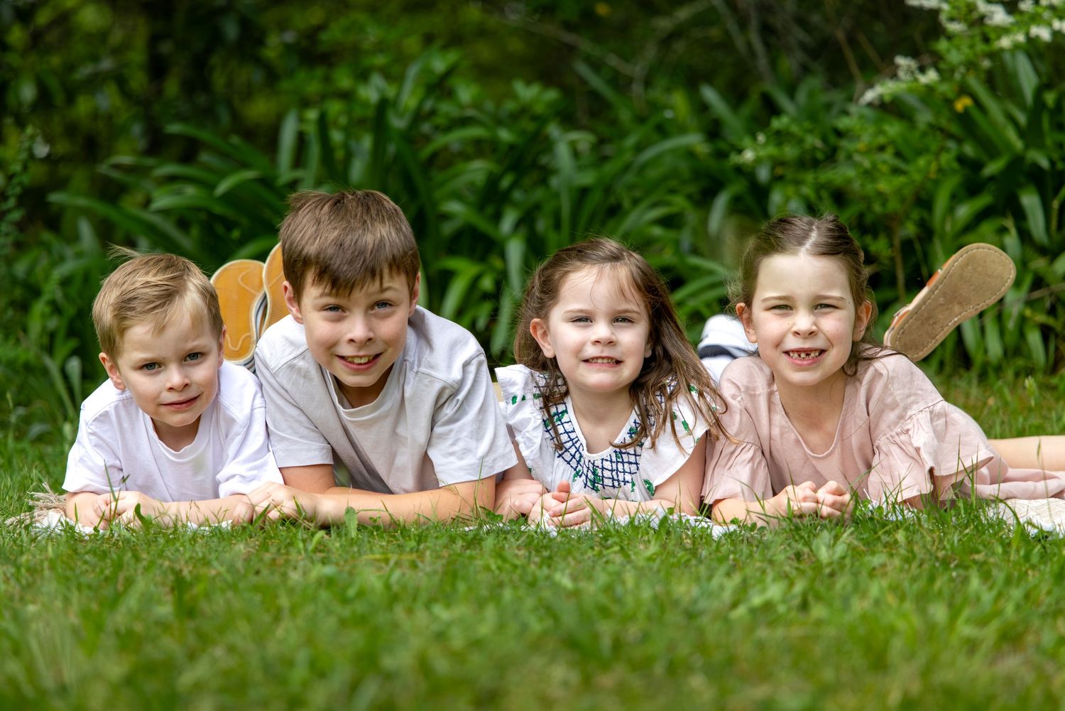 Family lying in grass together during outdoor photo session in garden setting Woodford Reserve in the Blue Mountains.