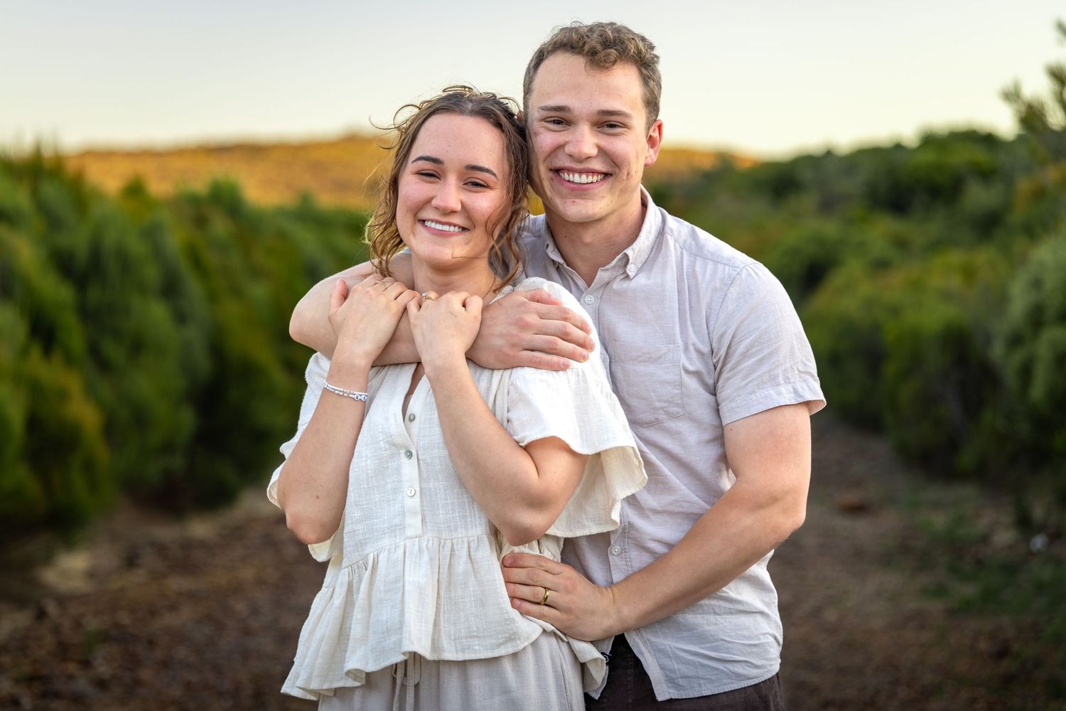 Couple laughing together in golden sunlight among vineyard rows at sunset at Lincoln's Rock in Wentworth Falls, Blue Mountains.