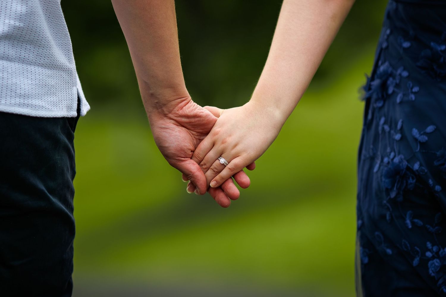 Close-up shot of couple holding hands against blurred natural background at Mount Annan Botanical Gardens.