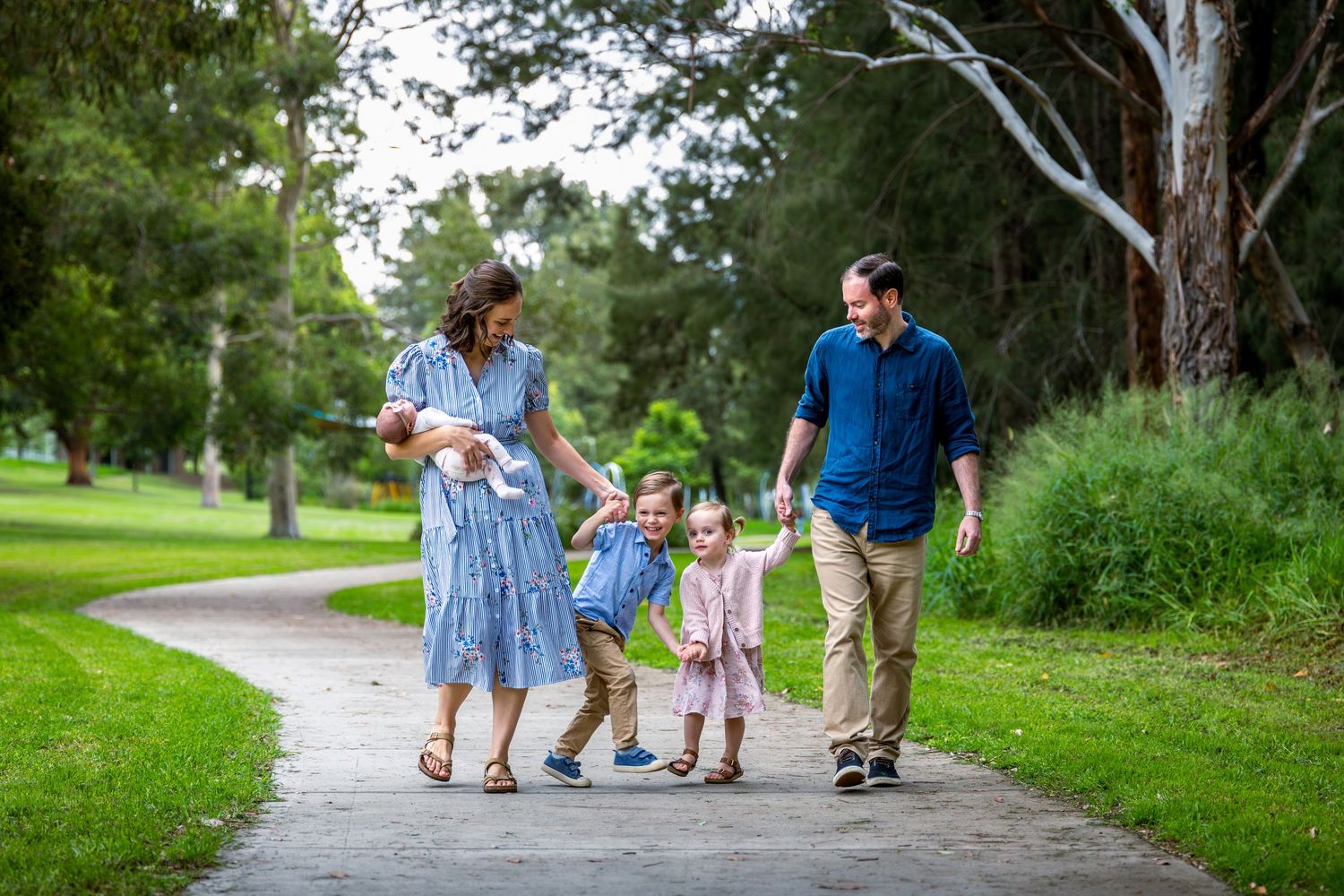 Family photography at at Tench Reserve, Nepean River. Happy family with three young children walking on a path.