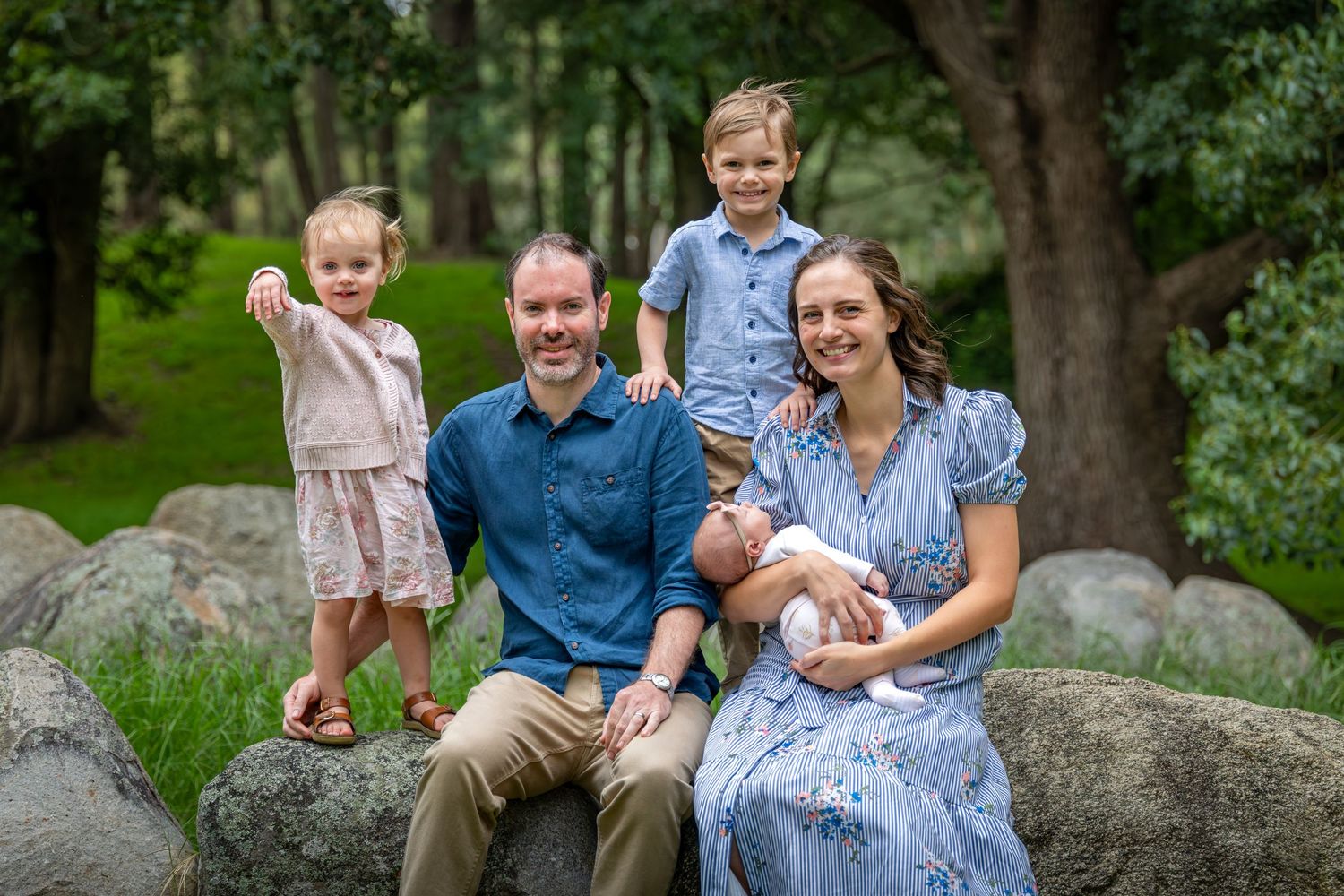 Family photography at at Tench Reserve, Nepean River. Happy family sitting on a rock with three young children.