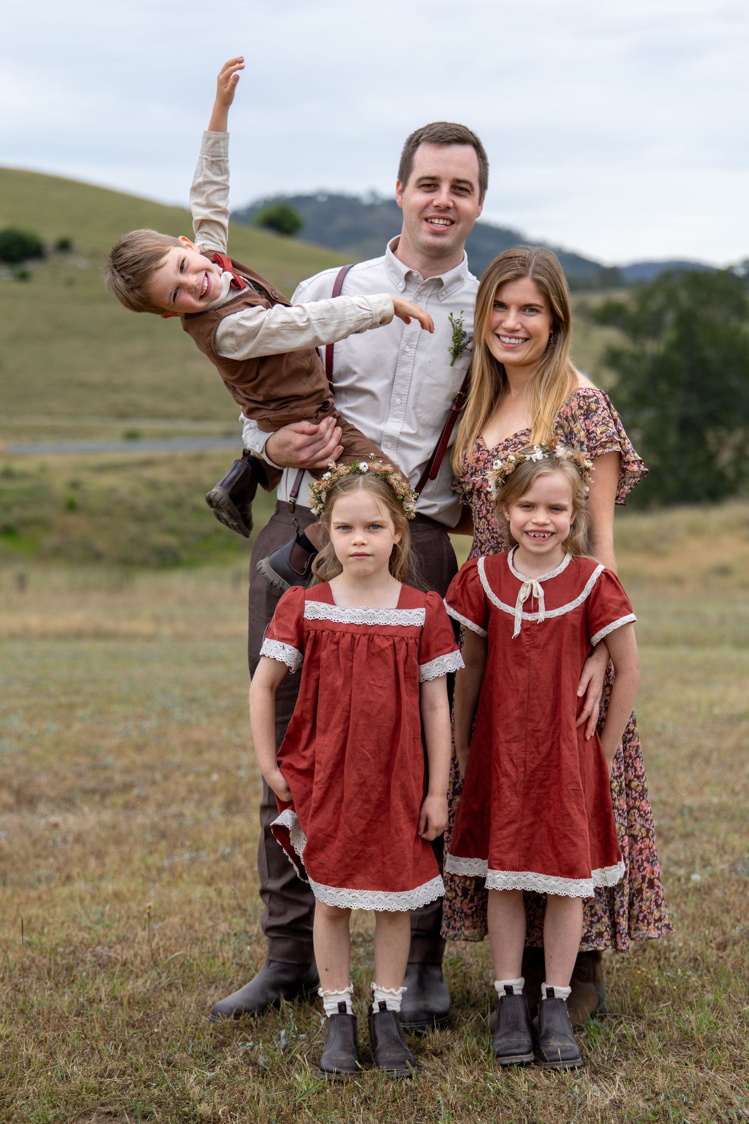 Family wedding portrait in field with children wearing matching red dresses and playful poses in Singleton, Hunter Valley.