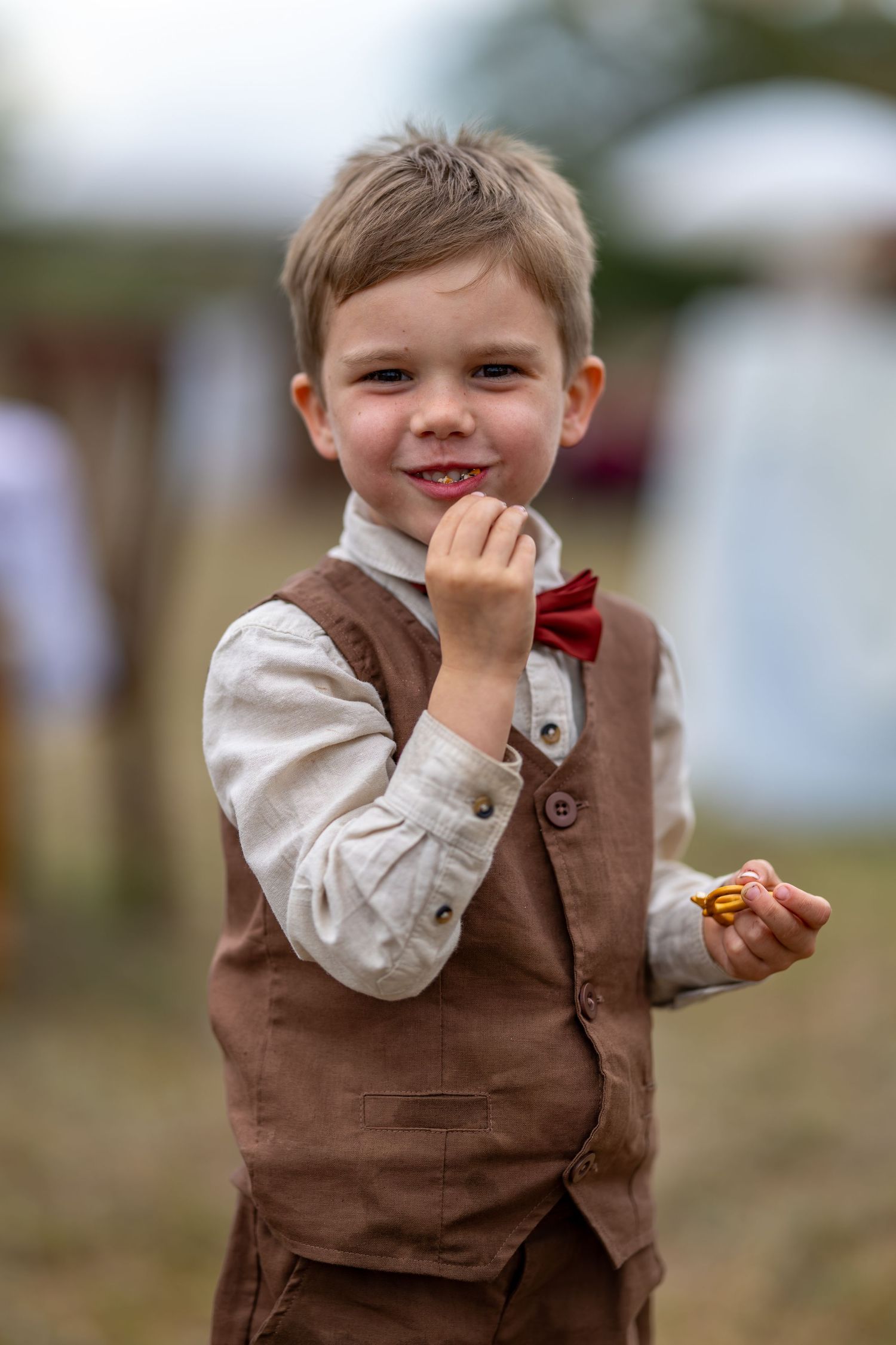 Young child in brown vest and white shirt smiling playfully at a wedding in Singleton, Hunter Velley.