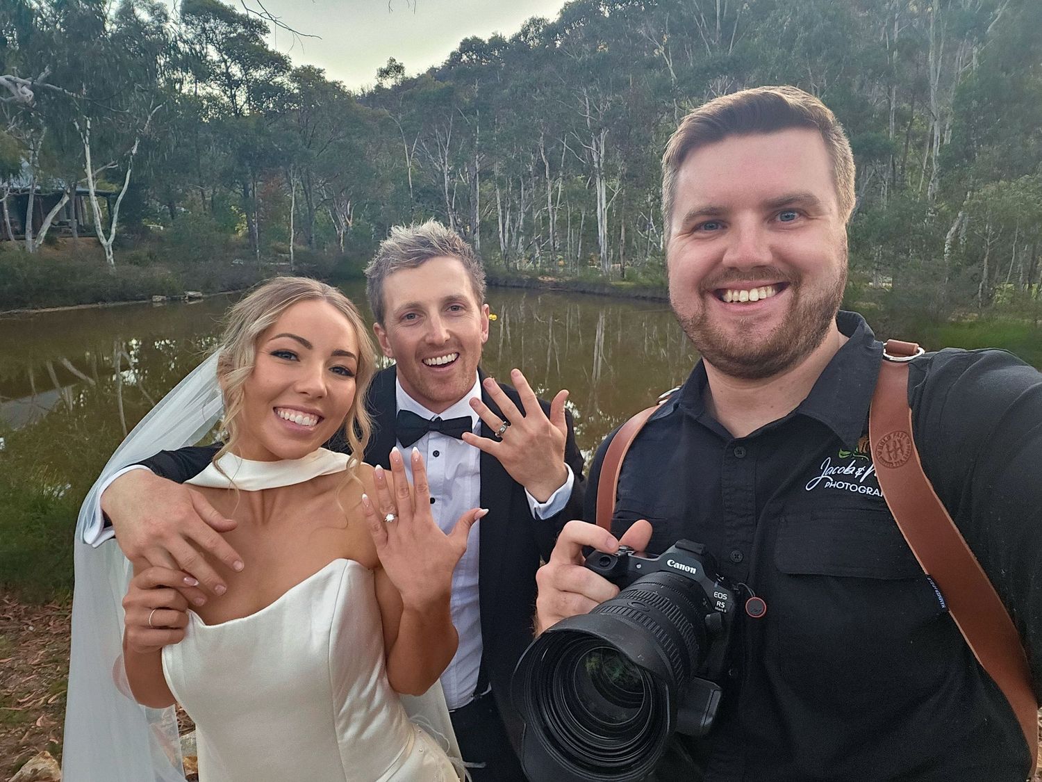 Bride and groom showing wedding rings with Jacob & Mim Photography posing with them smiling at Lawson Park, Hartley Vale.
