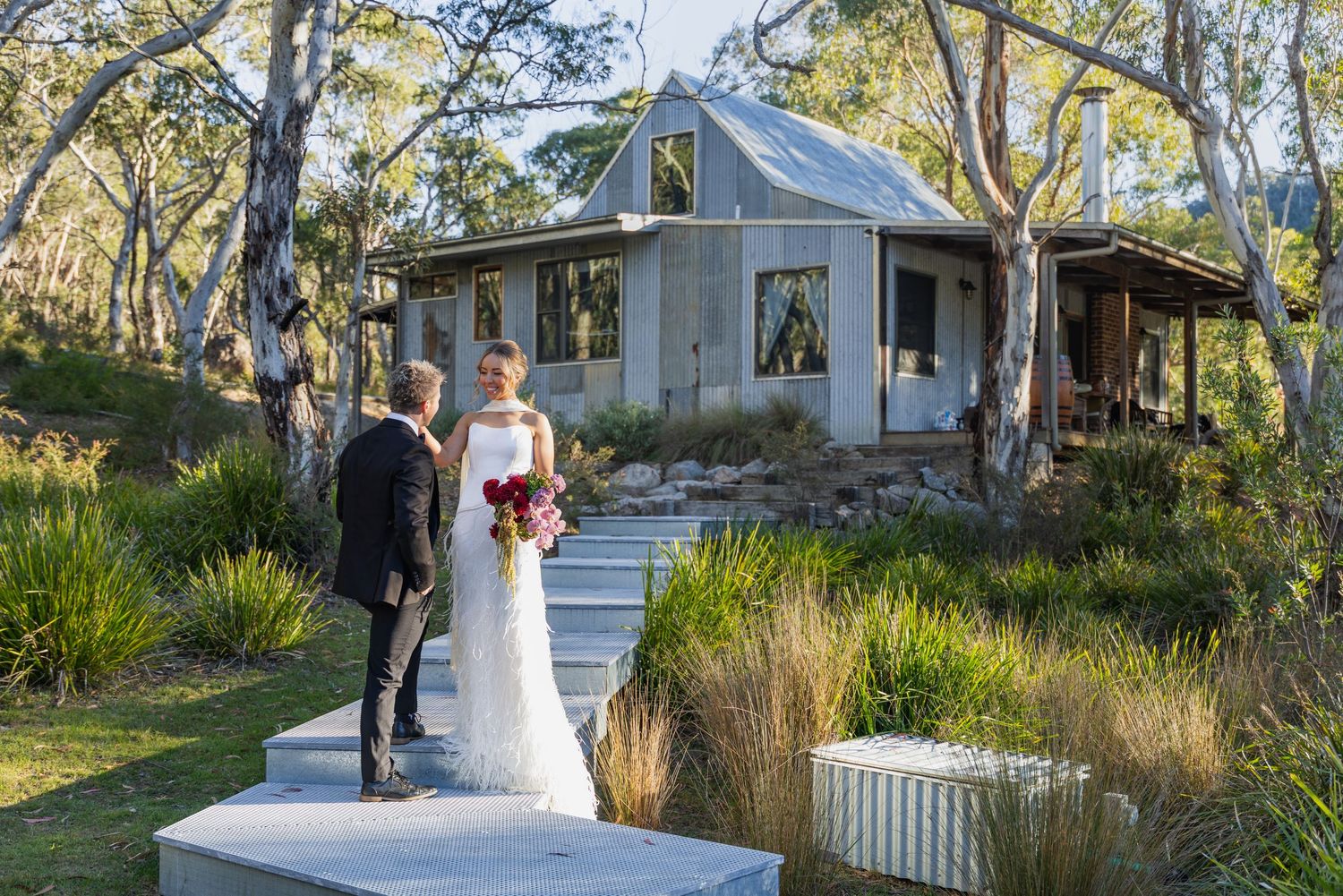 Bride and groom stand outside a rustic cottage surrounded by native Australian gardens on their wedding day at Lawson Park, Hartley Vale.