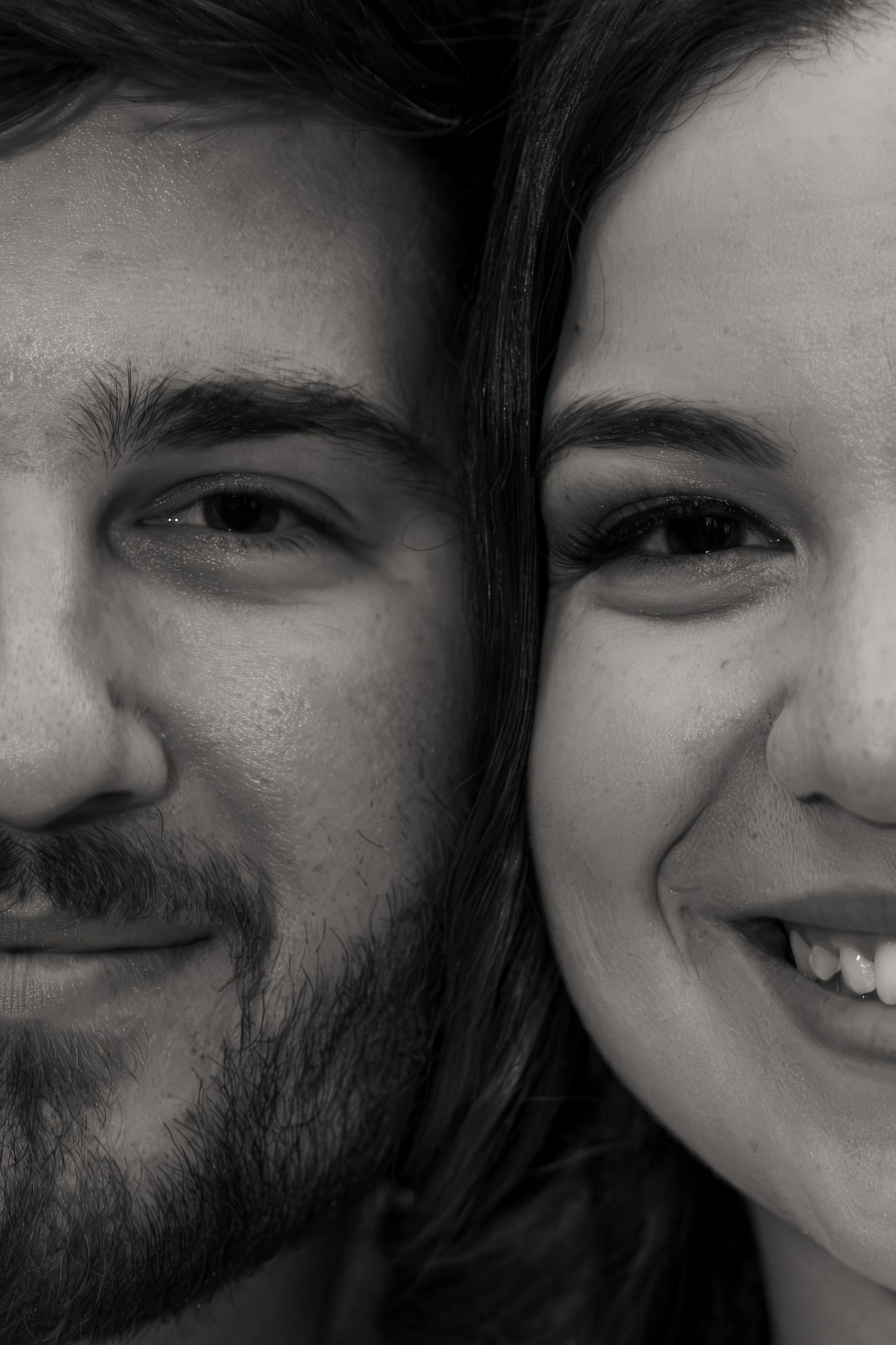 Black and white close-up portrait of a smiling man and woman with their faces side by side.