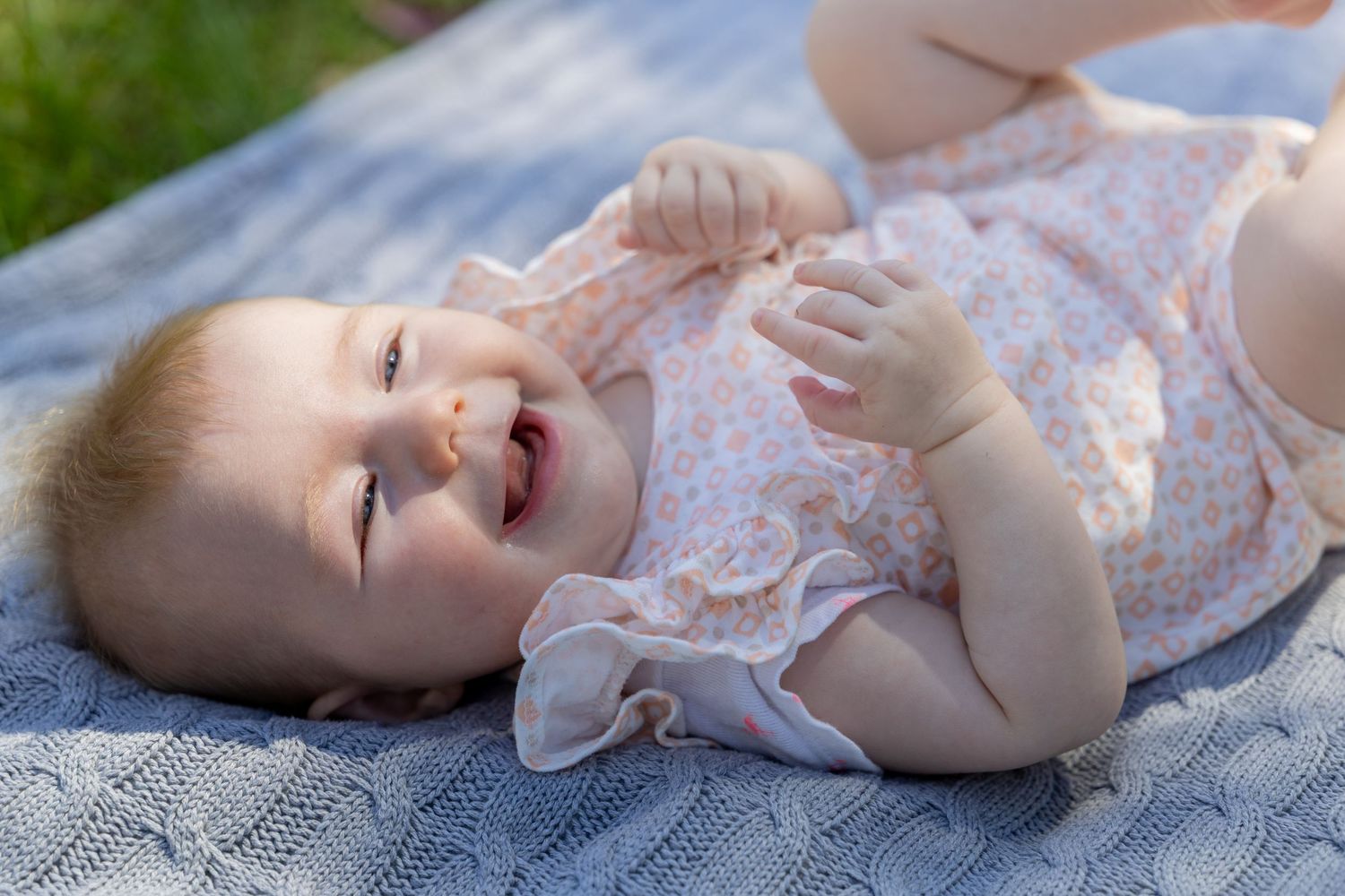 Baby in floral outfit lying on blanket outdoors with natural lighting at Tench Reserve, Nepean River.