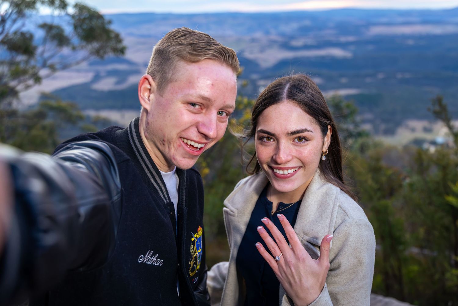 Couple taking a selfie at Mount Blackheath Lookout, woman showing off engagement ring, celebrating proposal outdoors.