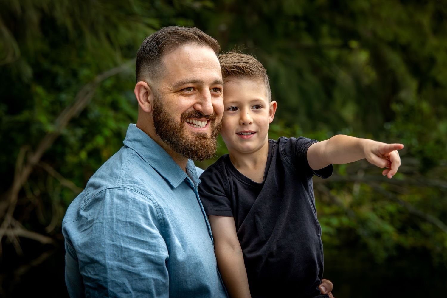 A heartwarming outdoor portrait of a father and son pointing and smiling at Tench Reserve, Nepean River.