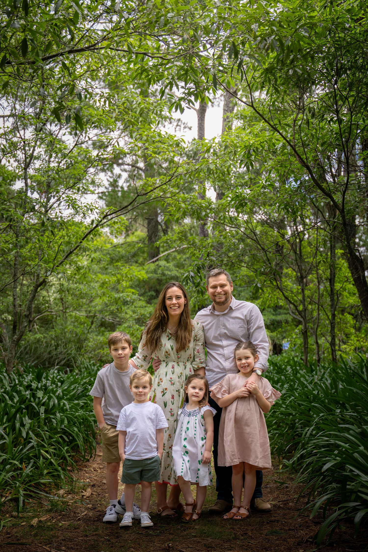 Family group photo in coordinated outfits standing among lush garden greenery at Woodford Reserve in the Blue Mountains.