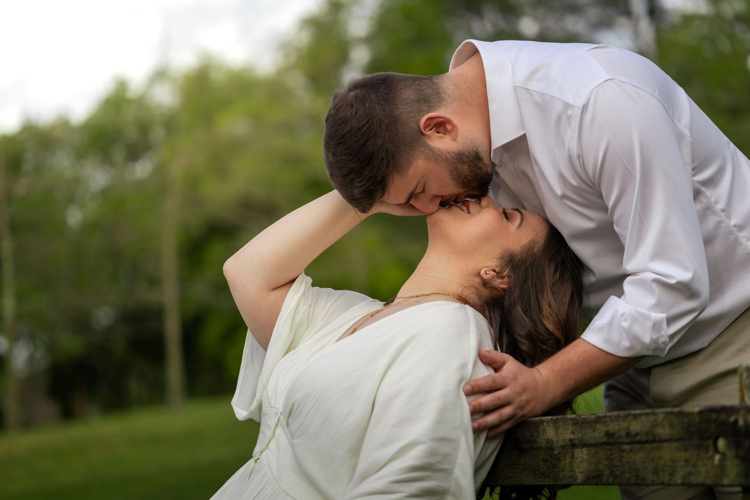 Romantic couple sharing a kiss outdoors in a lush green park in Blackheath, Blue Mountains during an engagement photo session.