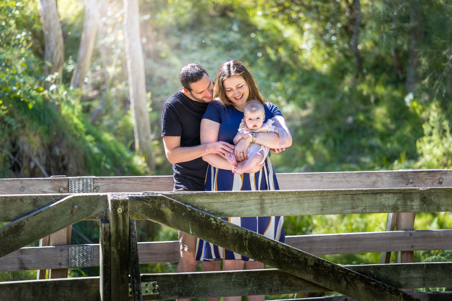 A family shares an intimate moment together on a wooden bridge at Euroka Clearing in Glenbrook, Blue Mountains.