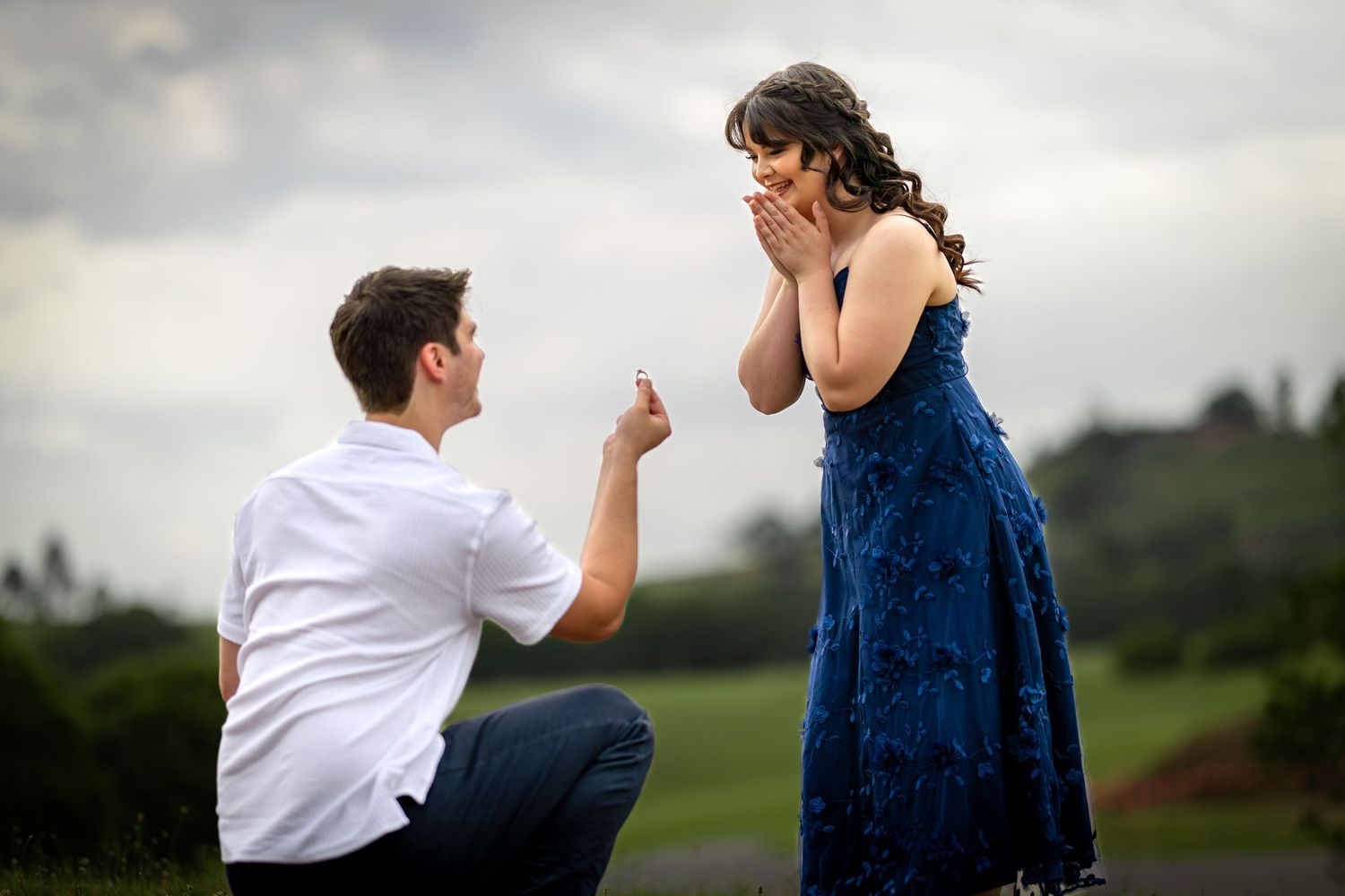 A romantic proposal sequence on rolling hills shows a couple in white and navy blue as they share a special moment.