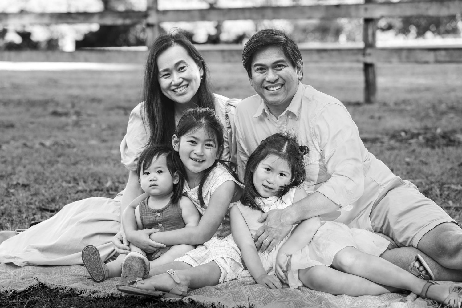 Family in white clothing relaxes together on a blanket during an outdoor photo session at Tench Reserve, Nepean River.
