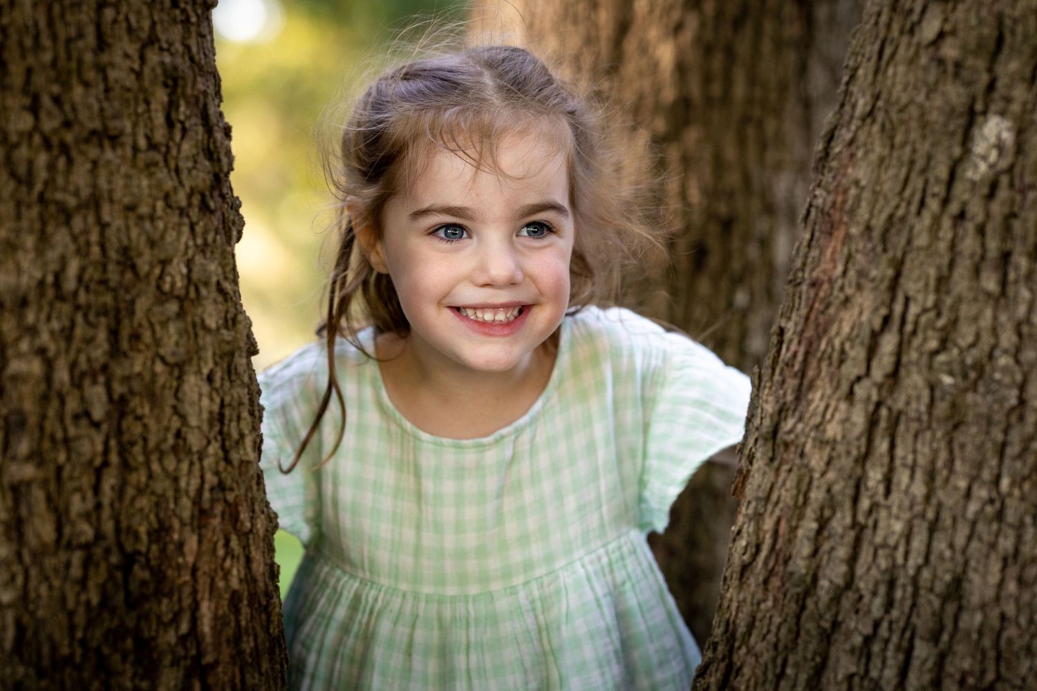 A series of close-up portraits showing a child in a gingham dress against a blurred natural background at Tench Reserve, Nepean River.