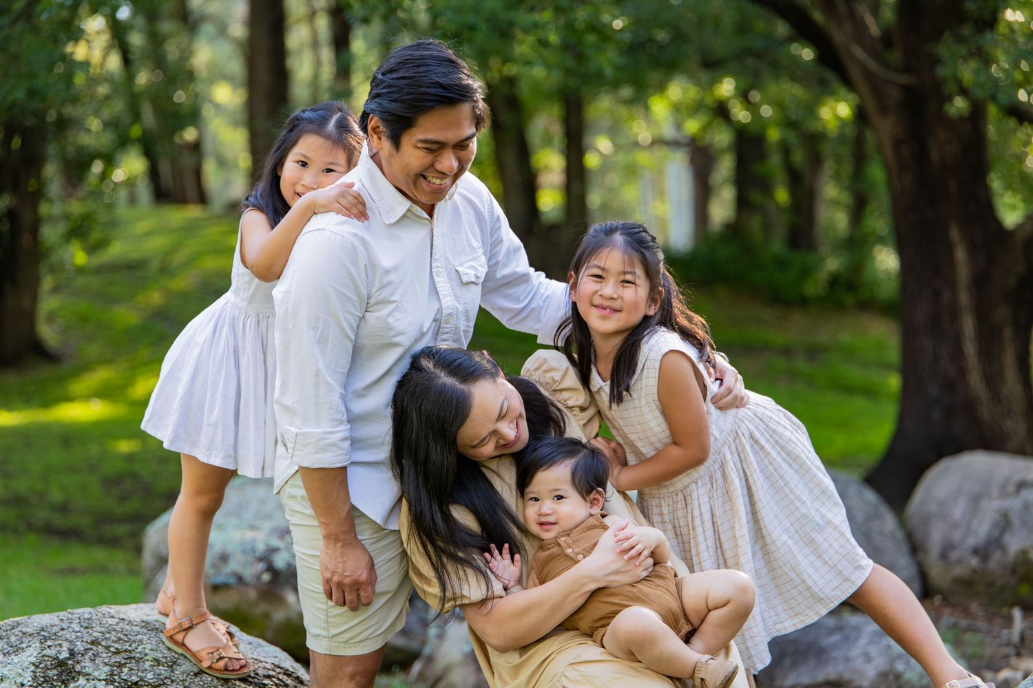 Family enjoying playful moments together in a lush green park setting during a photo session at Tench Reserce, Nepean River.