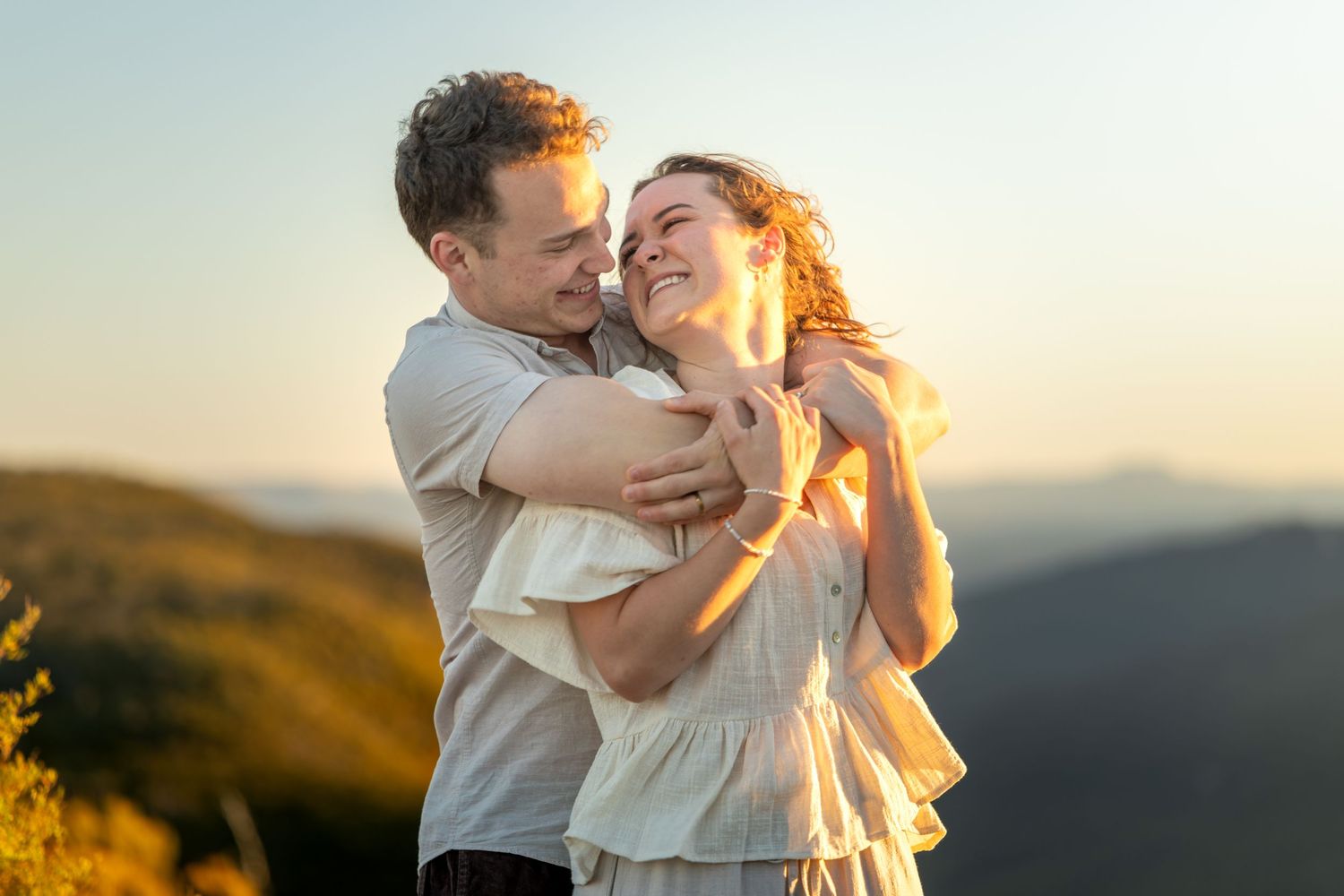 A romantic couple embraces in golden sunset at Lincoln's Rock in Wentworth Falls, Blue Mountains.
