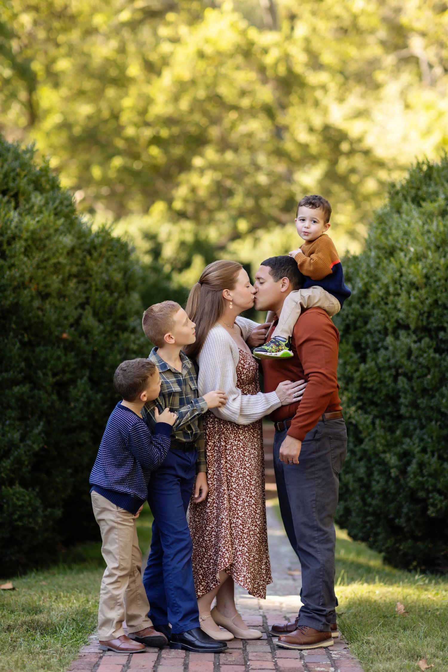 Children playing together near green bushes in afternoon sunlight.