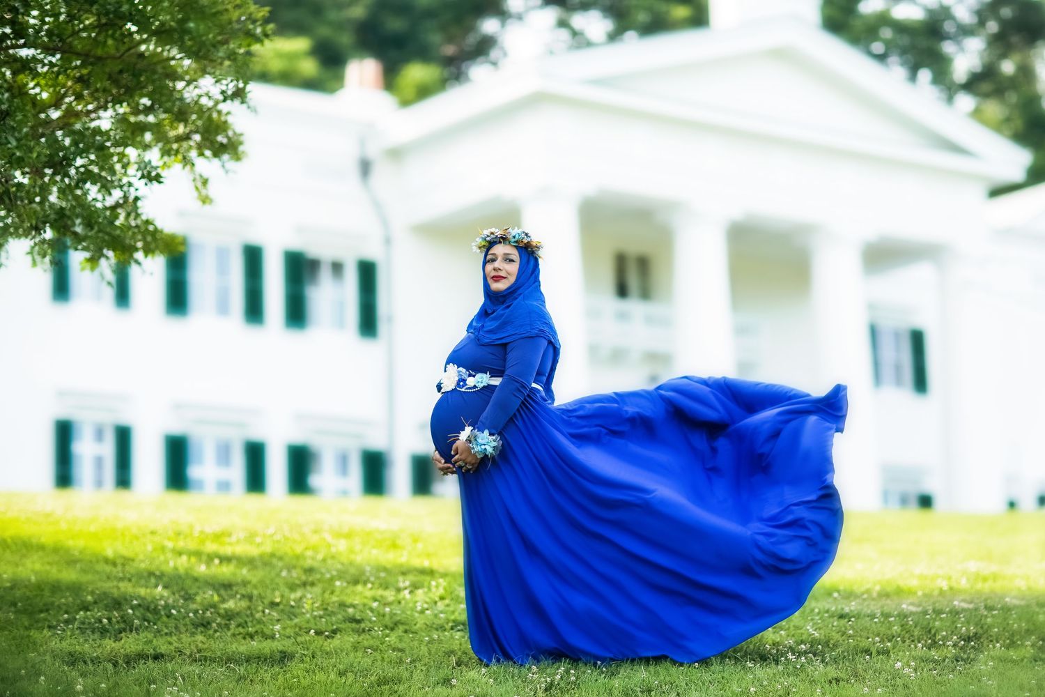 Vibrant blue dress billows elegantly against white colonial architecture.