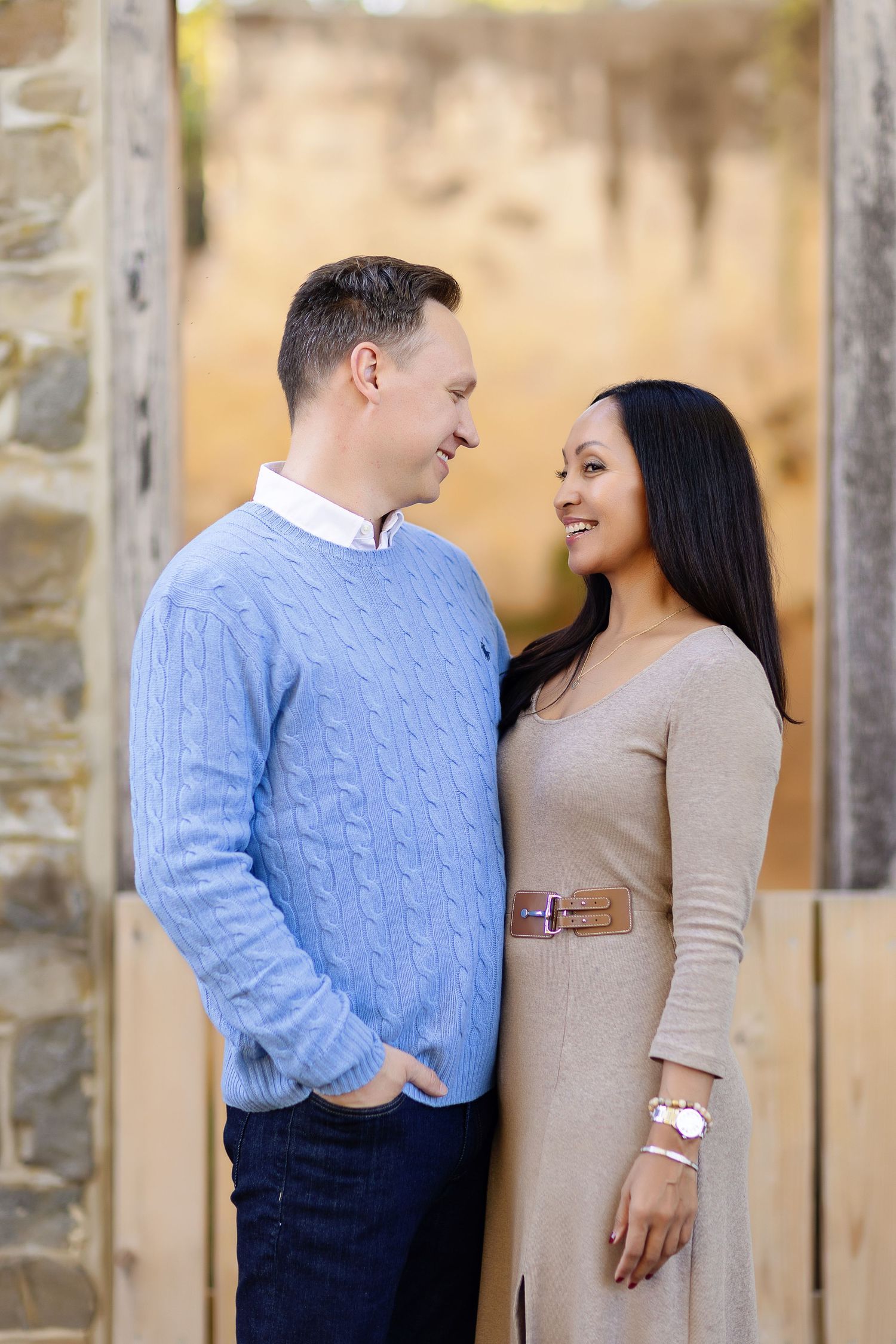 A couple shares intimate moments in a stone archway wearing coordinated blue and beige outfits.