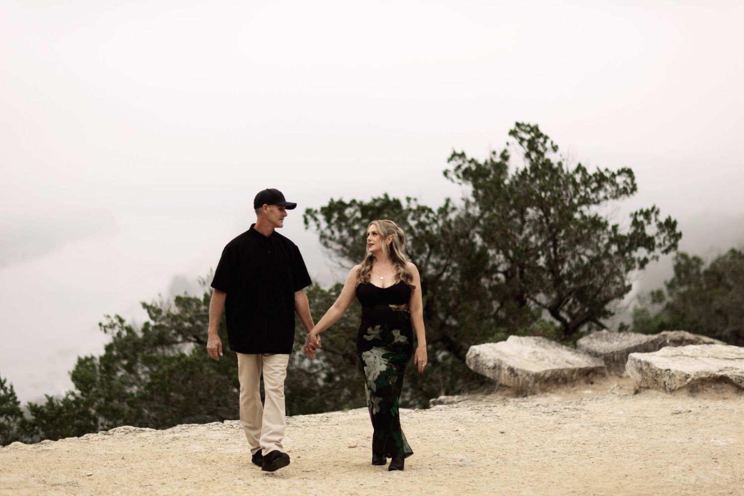Couple walking along a scenic cliff path overlooking natural landscape.