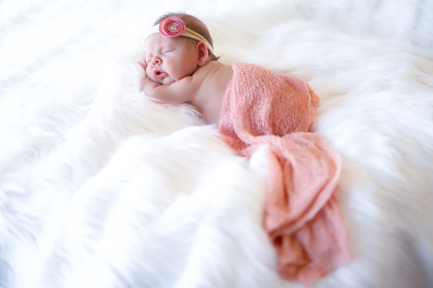 Soft, dreamy newborn photography session with pink and white tones.