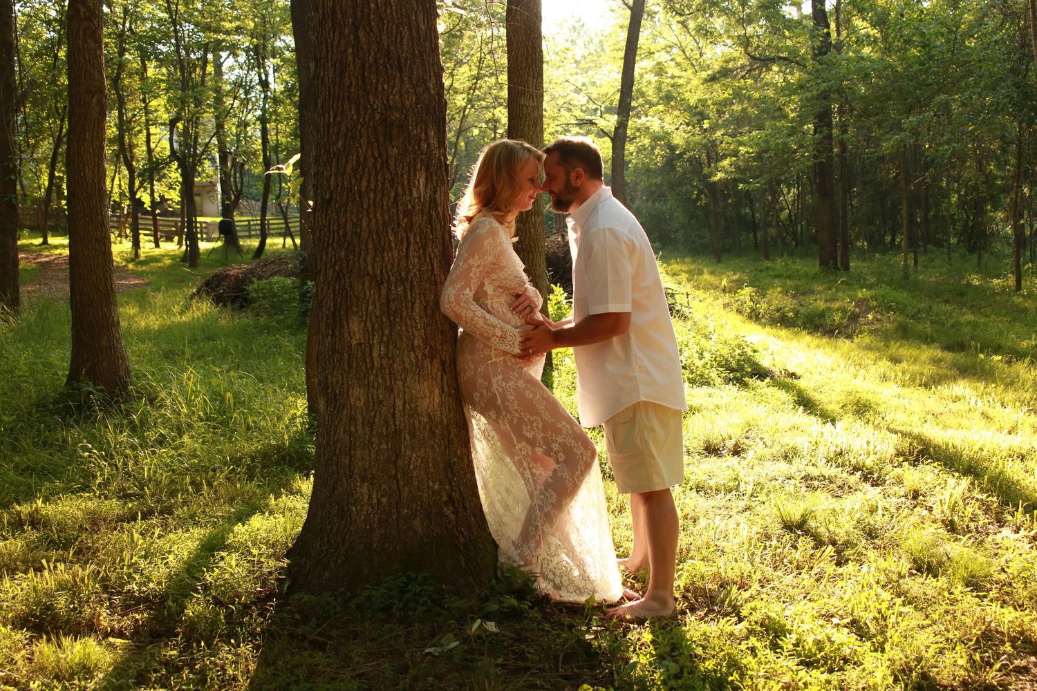 Golden sunlight streams through trees as couple shares romantic moment.