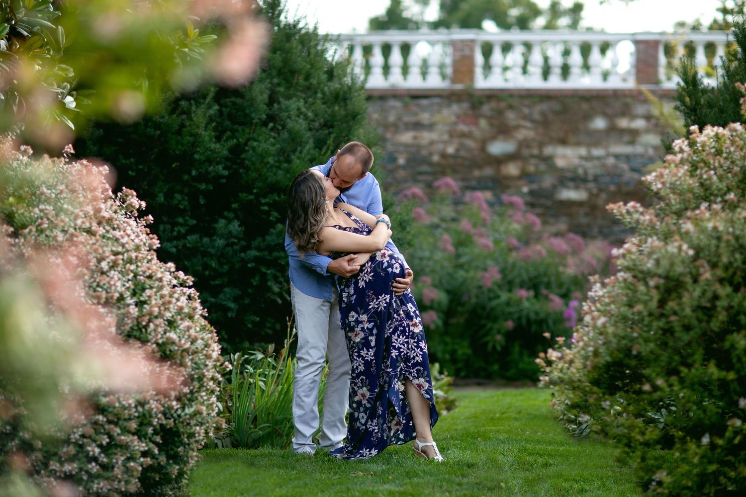 A romantic outdoor photo session in a garden setting with white columns and flowering bushes.