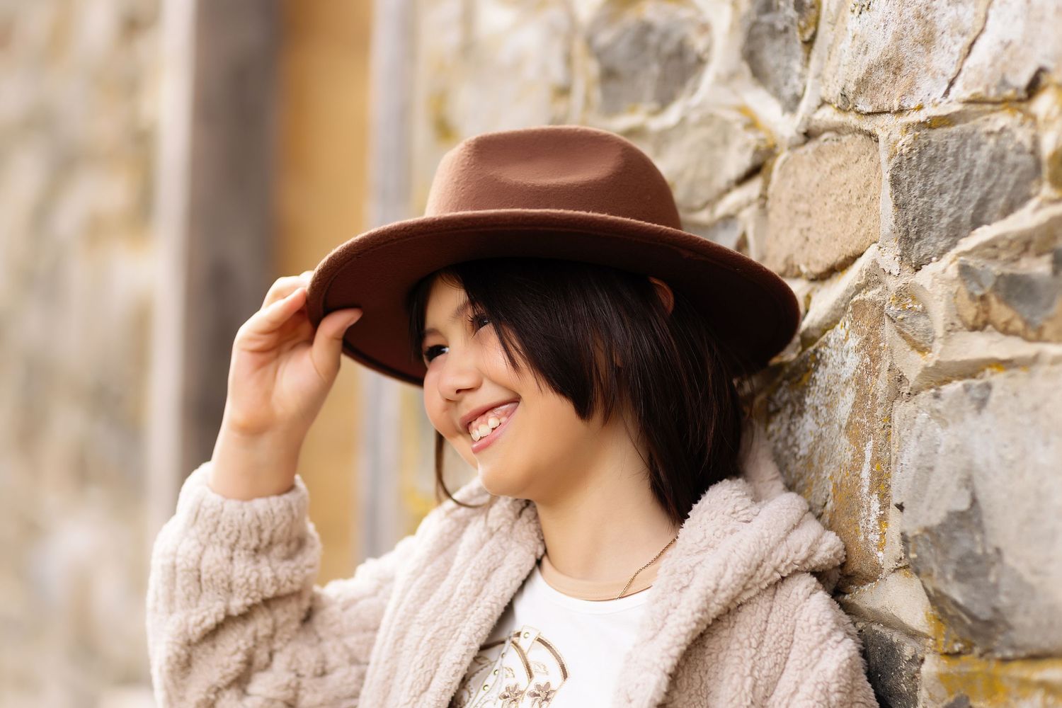 Portrait series featuring cozy winter fashion against a rustic stone wall.