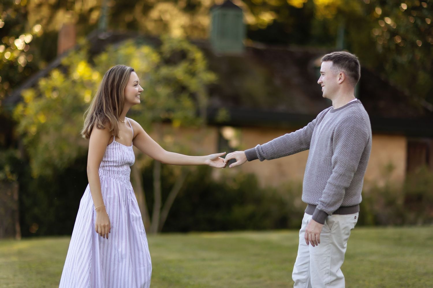A couple walks playfully through a garden setting during a romantic photoshoot.
