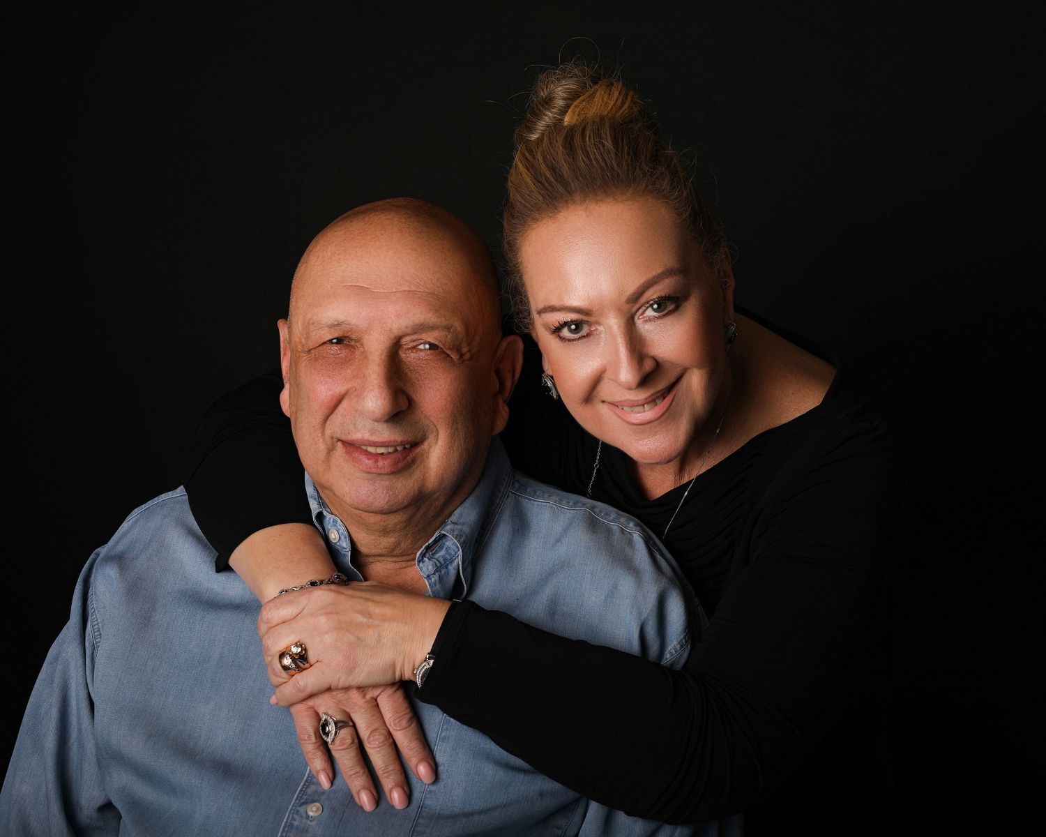 Intimate studio portrait against dark background with dramatic lighting.
